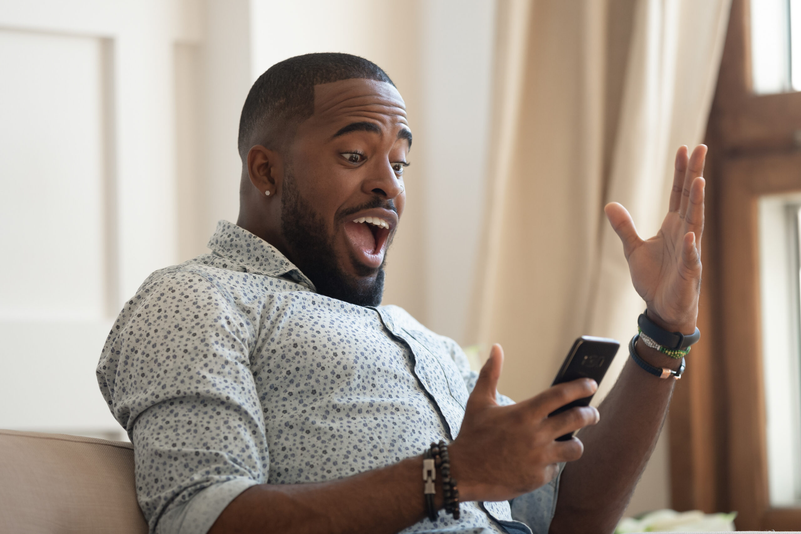 Surprised,Happy,African,Man,Holding,Phone,Looking,At,Cellphone,Read